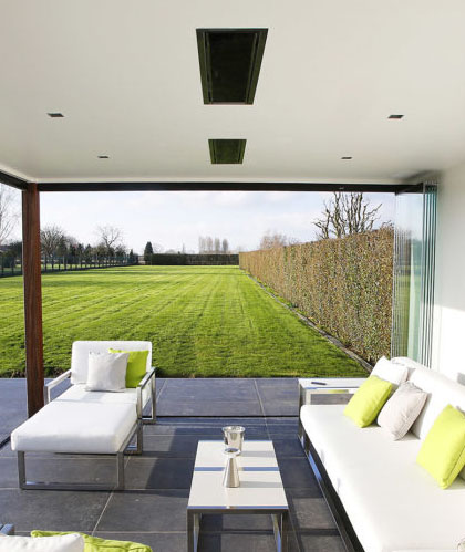Two  Bromic Platinum Series recessed heaters in a modern covered patio overlooking a manicured lawn.