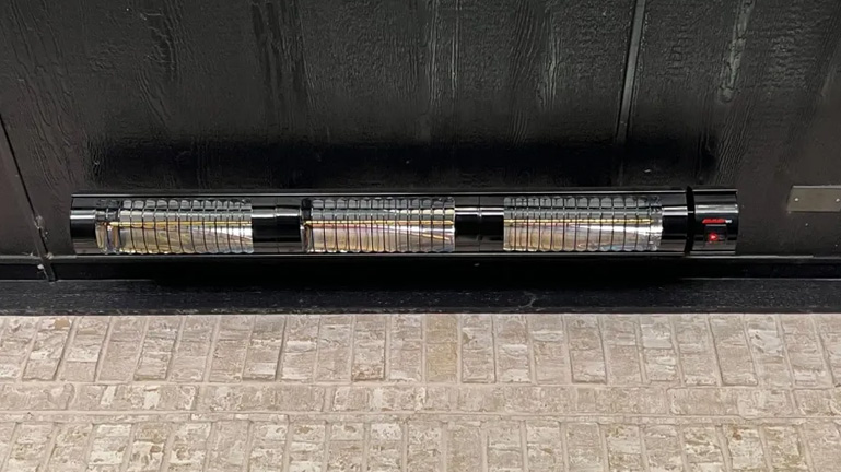 golden tube heater mouted on a dark wood covered patio ceiling