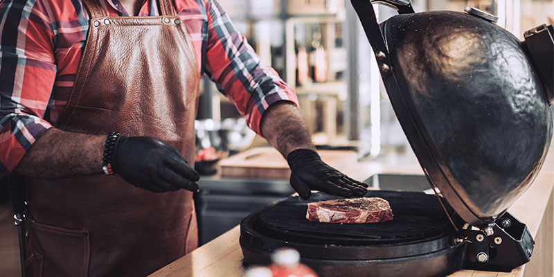 a man grilling seasoned steak on a tabletop grill
