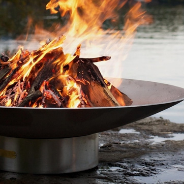 Lit fire pit next to a lake