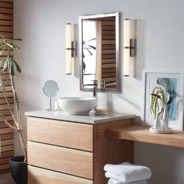 two modern bathroom vanity lights on either side of a mirror above a modern vanity